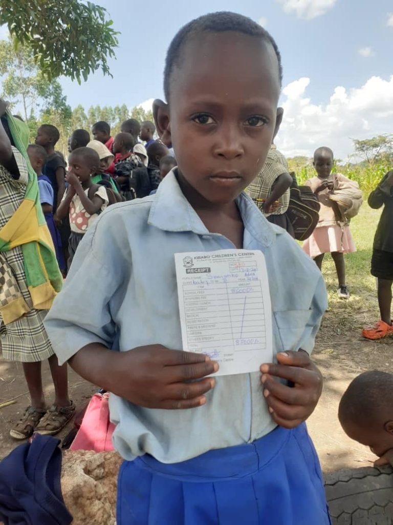 Semambo Abel holding a payment receipt for his school fees